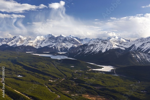 Green Valley and Distant Snowy Mountain Peaks Aerial Landscape View with Dramatic Sky on Horizon. Scenic Kananaskis Country Springtime Landscape, Canadian Rockies