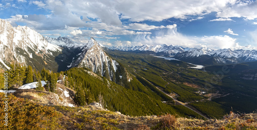 Green Valley and Distant Snowy Mountain Peaks Aerial Panoramic View with Dramatic Sky on Horizon. Scenic Kananaskis Country Springtime Landscape, Canadian Rockies