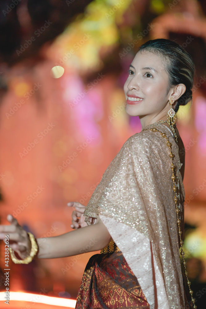 Woman in Thai traditional dress costume, Asian woman wearing Thai dress walking around Ancient City at night.