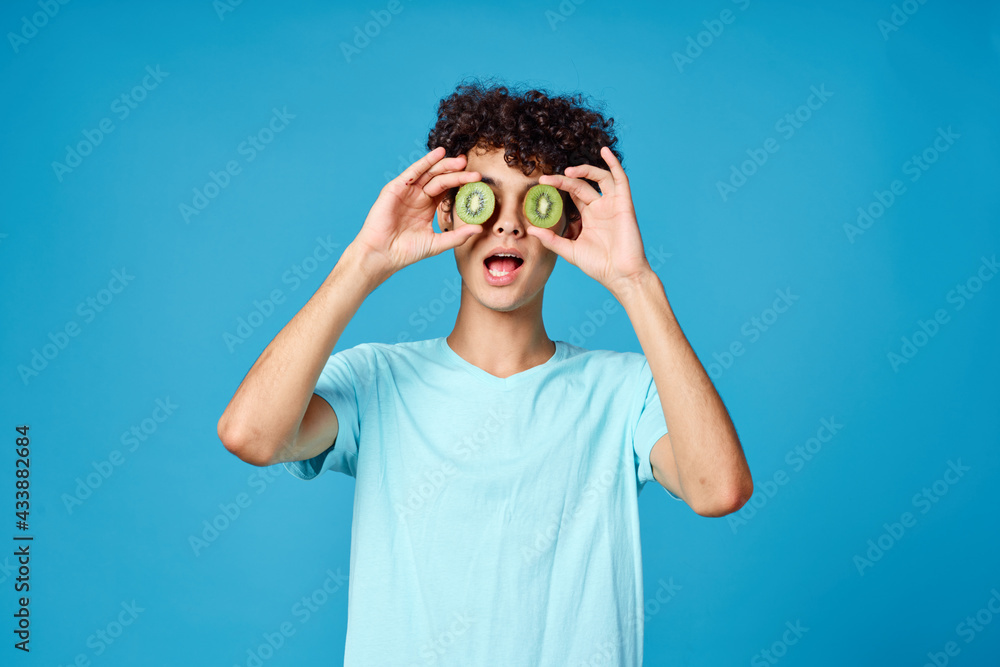 Cheerful guy curly hair kiwi near eyes isolated background Cheerful guy curly hair kiwi near eyes isolated background