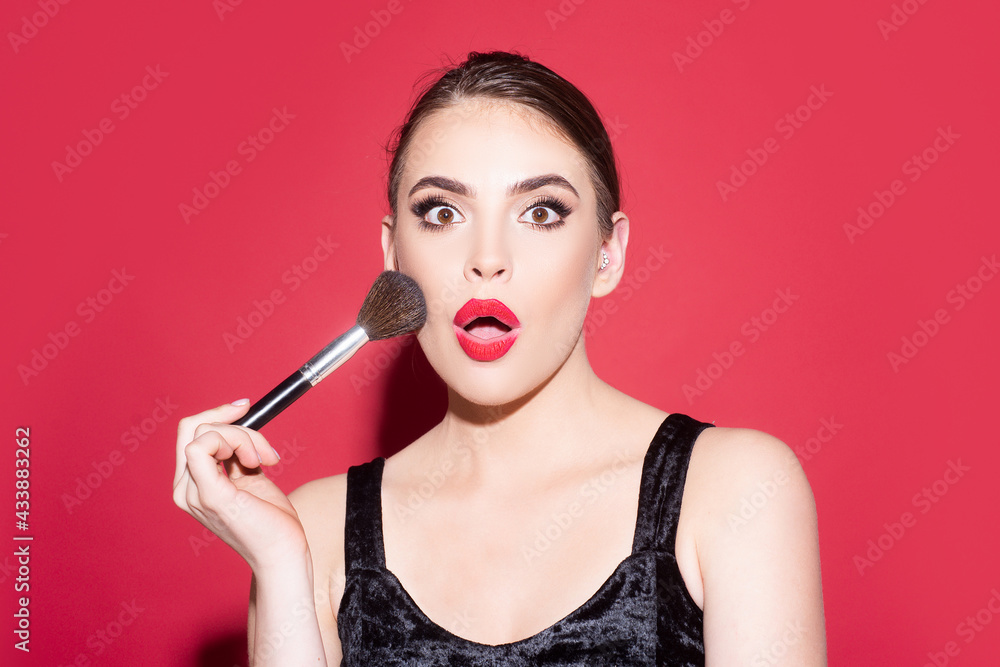 Obraz premium Portrait of amazed woman with makeup brush near face. Beautiful woman, female skin care, close up face beauty portrait.