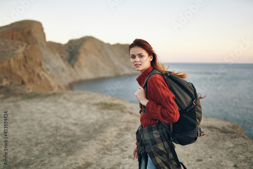 beautiful woman with a backpack in the mountains red sweater model hairstyle ocean sea
