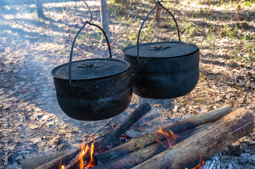 Two black, sooty pots hang over a burning fire.