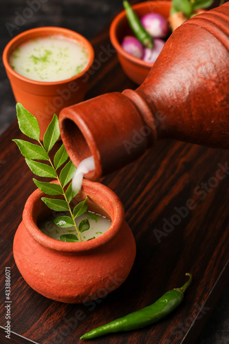 Pouring serving Spiced buttermilk , chaas , chaach , moru , sambharam , curd, lassi , yogurt, cool refreshing drink for hot summer in glass , Kerala, India Sri Lanka. Flavored Indian buttermilk. photo