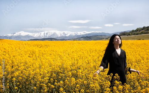 A beautiful girl in a black dress stands in the field. Spring photos