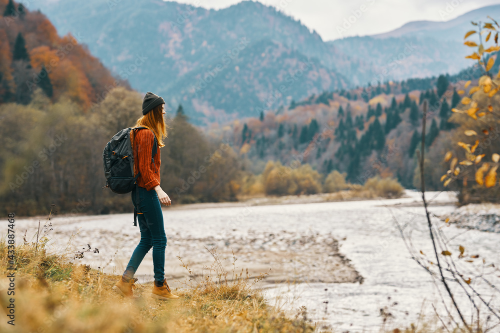 Fototapeta premium woman travels in autumn in the mountains near the river landscape model in full growth