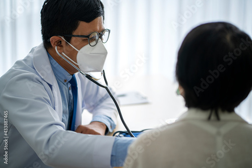 Indian male doctor using stethoscope exam eldery female patient for physical examine pneumonia lung sound checkup in hospital. Coronavirus, covid-19, medical and healthcare concept