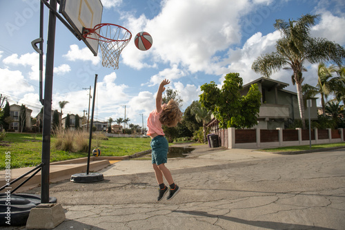 Cute little boy child jumping with basket ball for shot. Cute child playing basketball. © Volodymyr