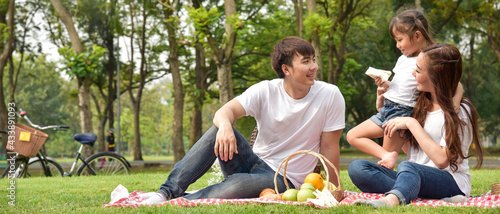 Portrait of happy Asian family, parents and daughter enjoying picnic meal in garden.Asian, Asian family, picnic, love, relationship, outdoors meal, park, family activities or happy garden concept