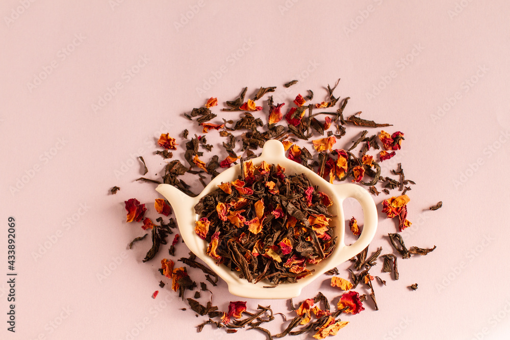Dry tea from rose petals and black tea leaves on a teapot-shaped plate Dry tea from rose petals and black tea leaves on a teapot-shaped plate