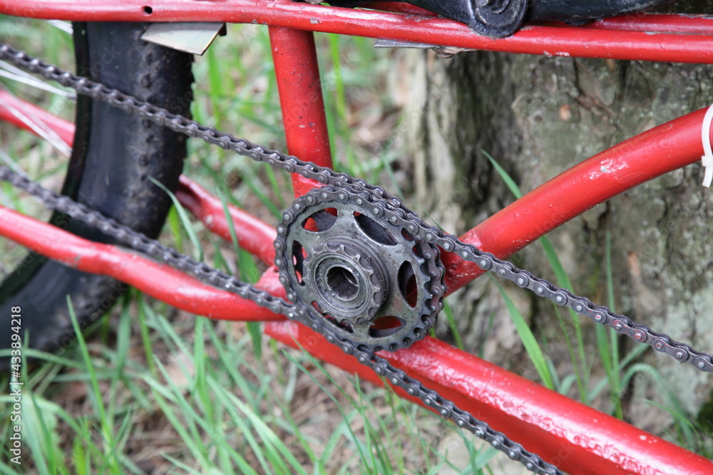 Old red custom bicycle internal star chain gear single speed , hardtail fatbike handmade frame close up on green grass background at summer day