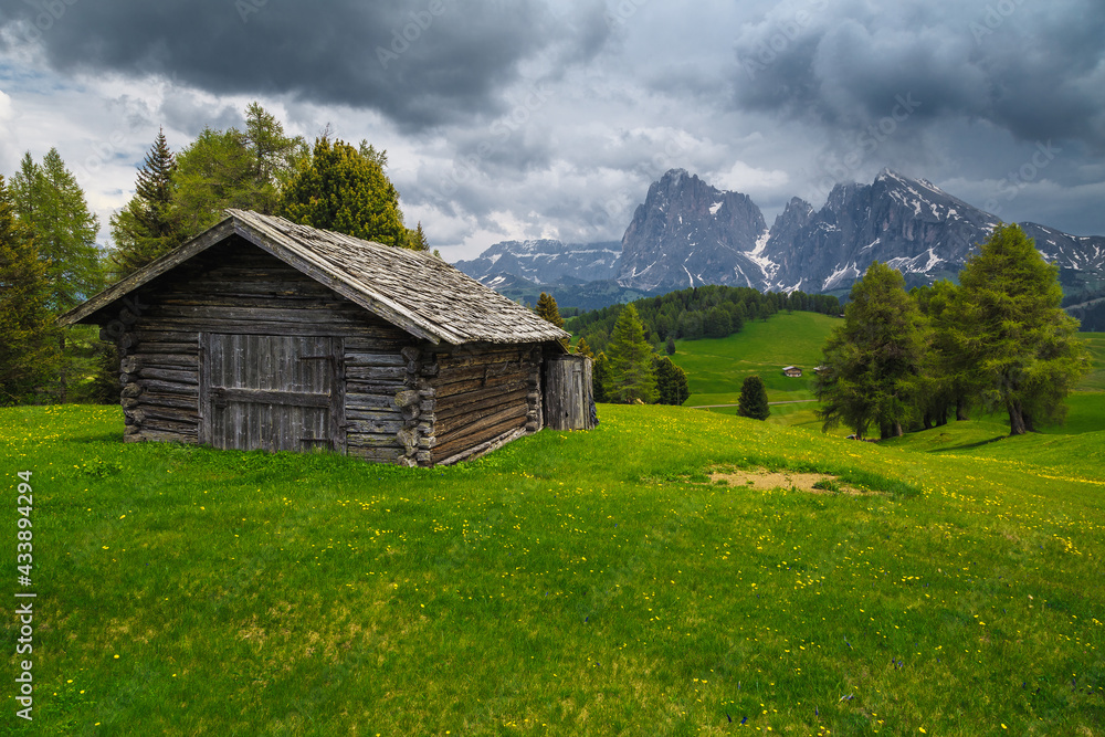 Cloudy alpine scenery with wooden hut and snowy mountains, Dolomites