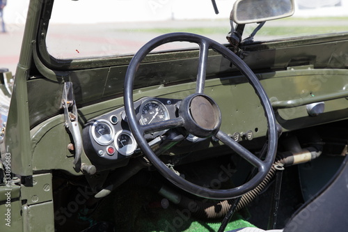 Steering wheel and dashboard in interior of old khaki vintage soviet military AWD car close up at Sunny day