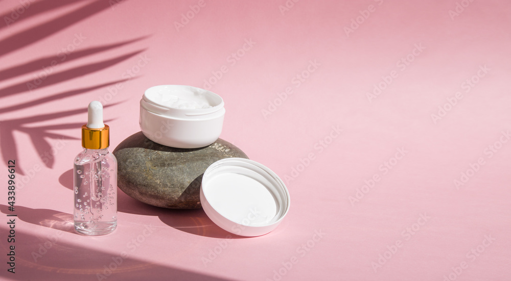 hand cream jar on the stone and dropper bottle of serum hyaluronic acid collagen with natural sunlight effect copy space on pink background hand cream jar on the stone and dropper bottle of serum hyaluronic acid collagen with natural sunlight effect copy space on pink background