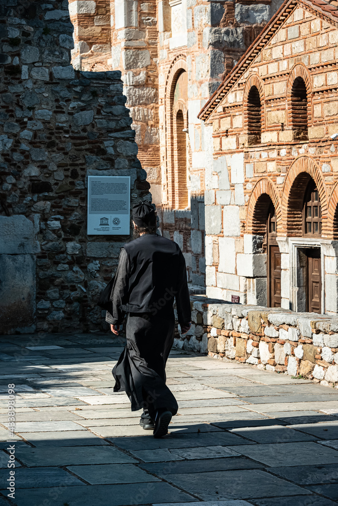 Monk walking over Square in Monastery. Hosios Loukas (Greek: Ὅσιος Λουκᾶς) is a historic walled monastery situated near the town of Distomo, in Boeotia, Greece. 10.08.2019