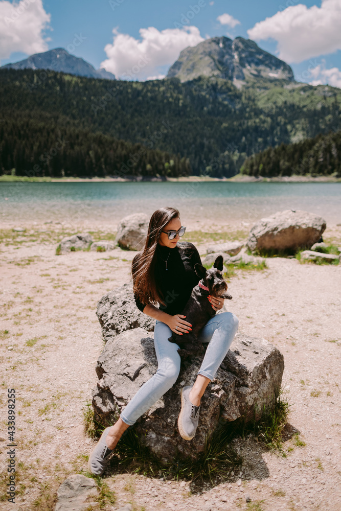 beautiful woman relax in mountains and lake view . Female model posing and relax in mountains with cute pet. Traveling with pet. Montenegro, Durmitor. the Black Lake. 