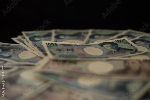 Blurred focus of pile of Japanese money in 1000 yen bills and 10000 yen bills on black background in soft focus