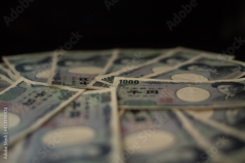 Blurred focus of pile of Japanese money in 1000 yen bills and 10000 yen bills on black background in soft focus
