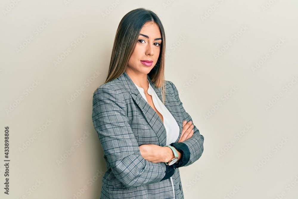 Young hispanic woman wearing business clothes with arms crossed gesture relaxed with serious expression on face. simple and natural looking at the camera. Young hispanic woman wearing business clothes with arms crossed gesture relaxed with serious expression on face. simple and natural looking at the camera.