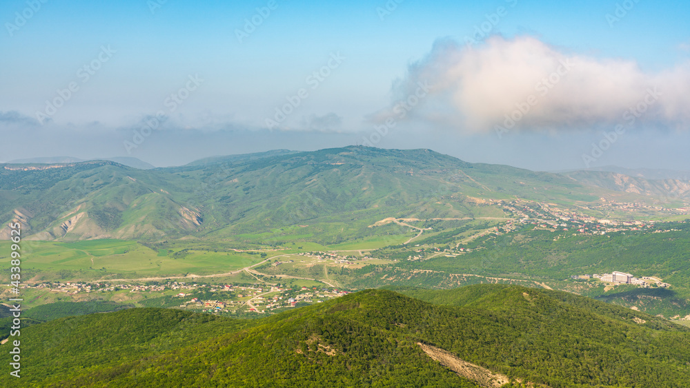 View of green mountains and villages in the valley. Wide angle panorama