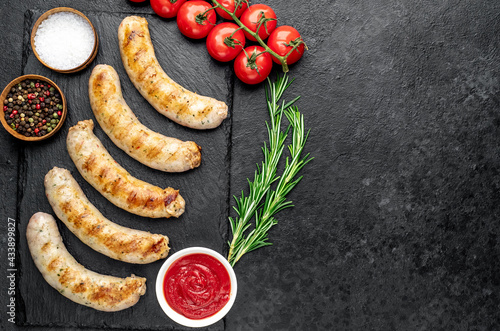grilled sausages with spices on a stone background with copy space for your text