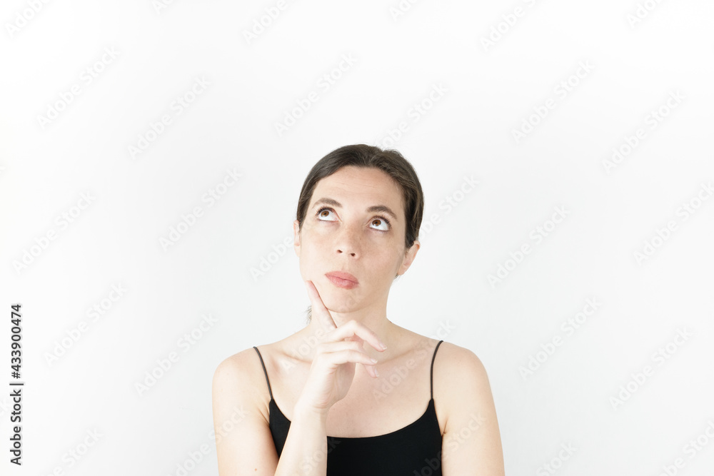 Young beautiful woman pointing up with fingers while thinking at white empty background Young beautiful woman pointing up with fingers while thinking at white empty background