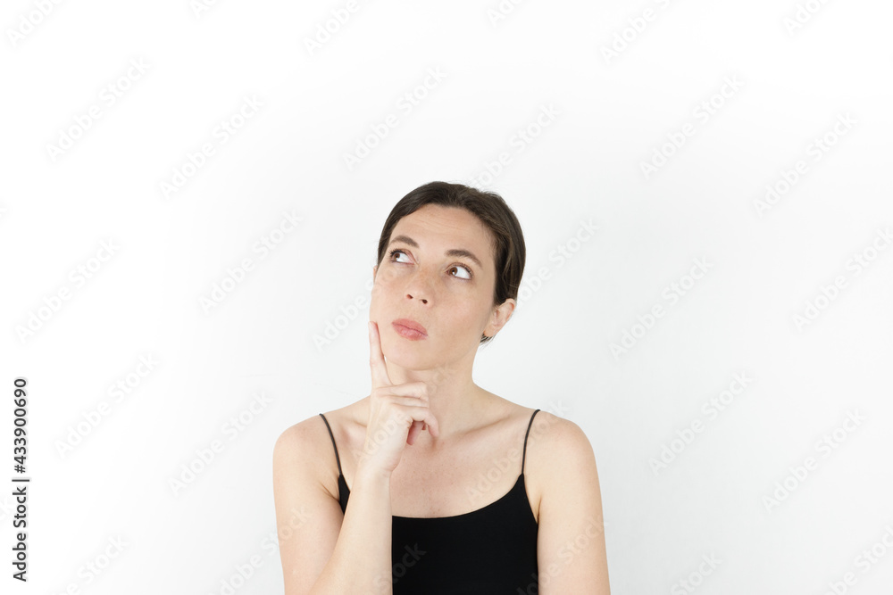 Young beautiful woman pointing up with fingers while thinking at white empty background Young beautiful woman pointing up with fingers while thinking at white empty background