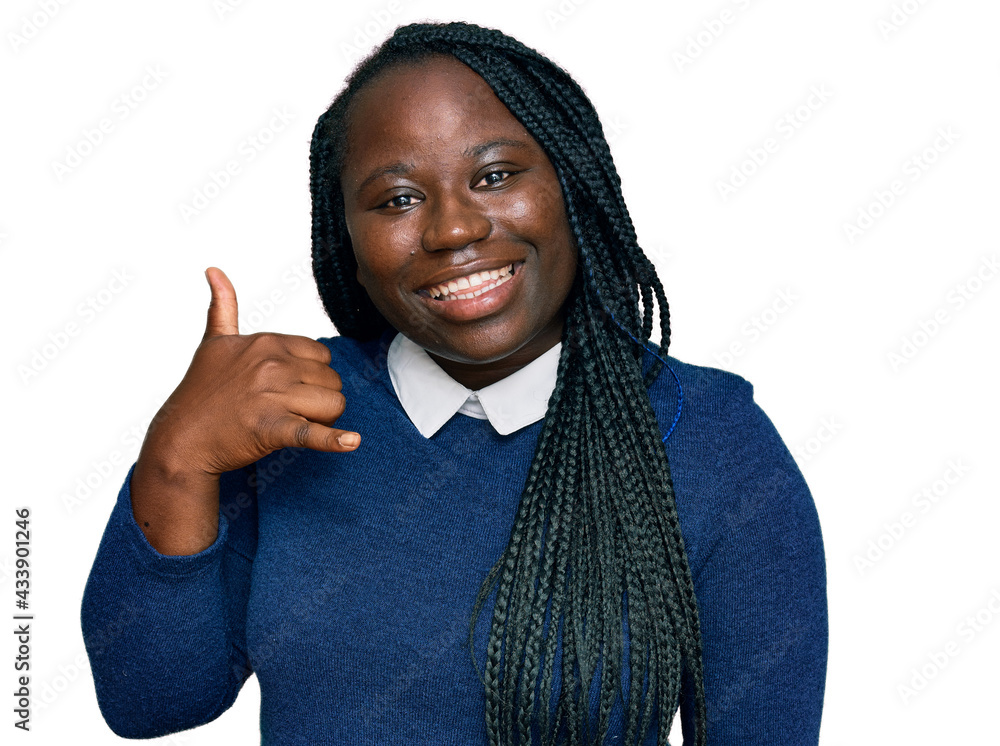 Young black woman with braids wearing casual clothes smiling doing phone gesture with hand and fingers like talking on the telephone. communicating concepts. Young black woman with braids wearing casual clothes smiling doing phone gesture with hand and fingers like talking on the telephone. communicating concepts.