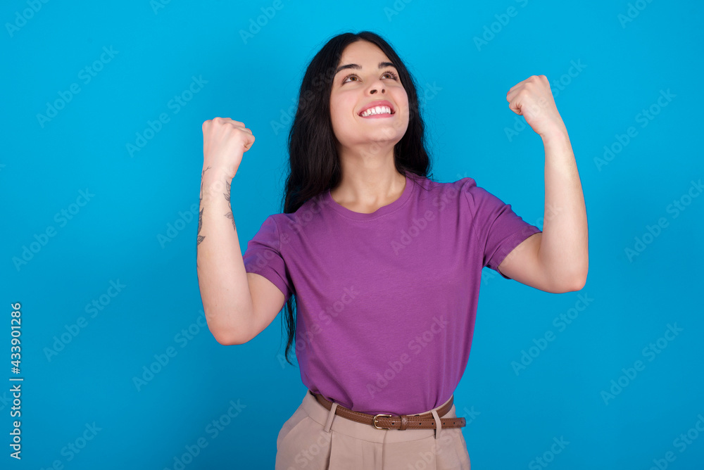 young beautiful tattooed girl wearing purple t-shirt having success being glad to achieve his goals. Victory and triumph concept. young beautiful tattooed girl wearing purple t-shirt having success being glad to achieve his goals. Victory and triumph concept.