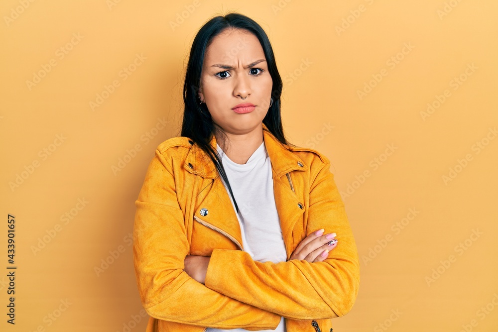 Beautiful hispanic woman with nose piercing wearing yellow leather jacket skeptic and nervous, disapproving expression on face with crossed arms. negative person. Beautiful hispanic woman with nose piercing wearing yellow leather jacket skeptic and nervous, disapproving expression on face with crossed arms. negative person.