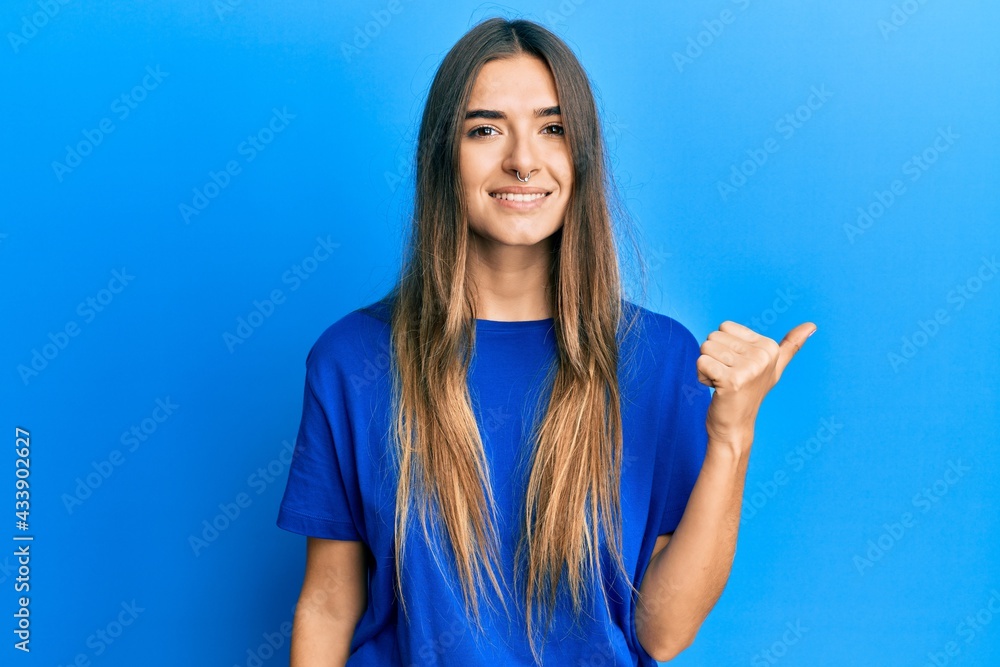 Fototapeta premium Young hispanic woman wearing casual clothes smiling with happy face looking and pointing to the side with thumb up.
