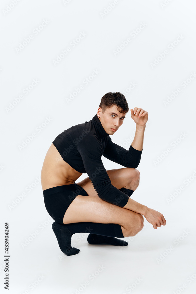 side view of a sporty man in shorts, socks and a sweater sits on a light background side view of a sporty man in shorts, socks and a sweater sits on a light background