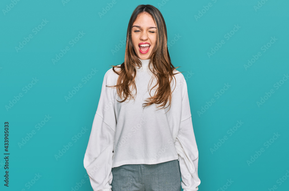 Young brunette woman wearing casual turtleneck sweater winking looking at the camera with sexy expression, cheerful and happy face. Young brunette woman wearing casual turtleneck sweater winking looking at the camera with sexy expression, cheerful and happy face.
