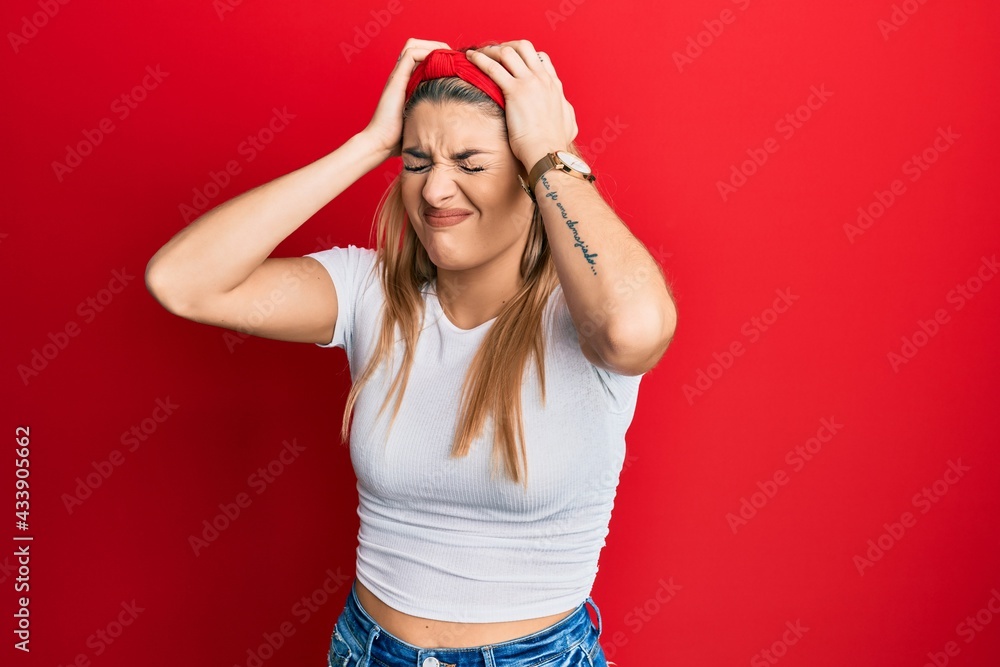 Young caucasian woman wearing casual white t shirt suffering from headache desperate and stressed because pain and migraine. hands on head. Young caucasian woman wearing casual white t shirt suffering from headache desperate and stressed because pain and migraine. hands on head.