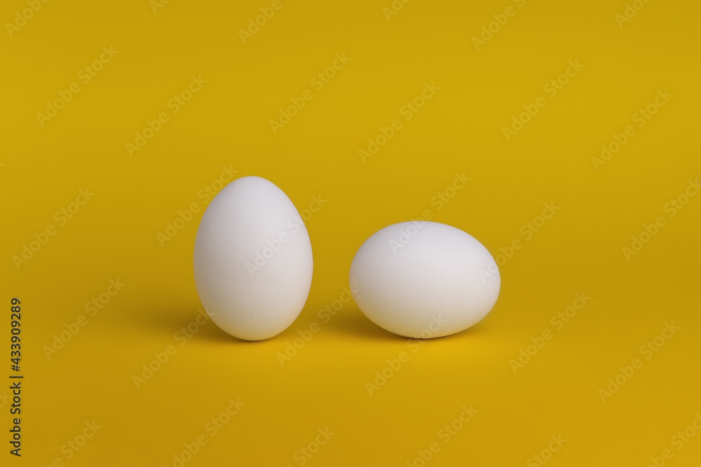 White eggs on a yellow background. The concept of minimalism. Side view. A card with a copy of the place for the text. White eggs on a yellow background. The concept of minimalism. Side view. A card with a copy of the place for the text.