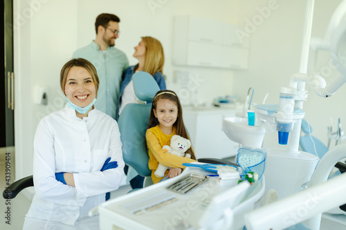 girl sitting in dental chair and smiling young kind female dentist in white coat looking at camera.