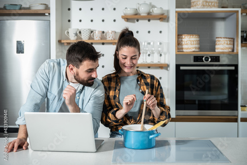Foto Young happy couple in the kitchen man teasing his girlfriend how she dont know t
