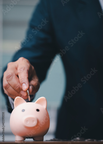 business man putting coins into the piggy bank.