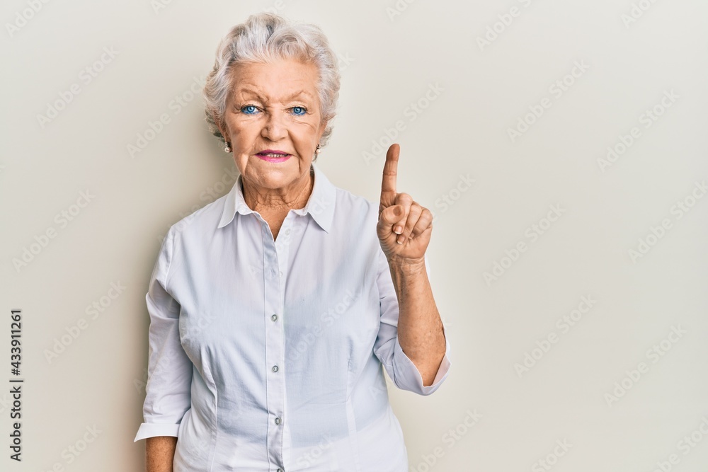 Senior grey-haired woman wearing casual clothes smiling with an idea or question pointing finger up with happy face, number one