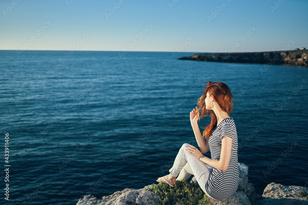 romantic woman on a rock near the sea in the mountains sunset summer back view romantic woman on a rock near the sea in the mountains sunset summer back view