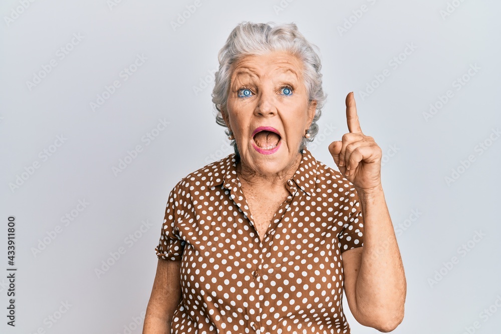 Senior grey-haired woman wearing casual clothes pointing finger up with successful idea. exited and happy. number one. Senior grey-haired woman wearing casual clothes pointing finger up with successful idea. exited and happy. number one.