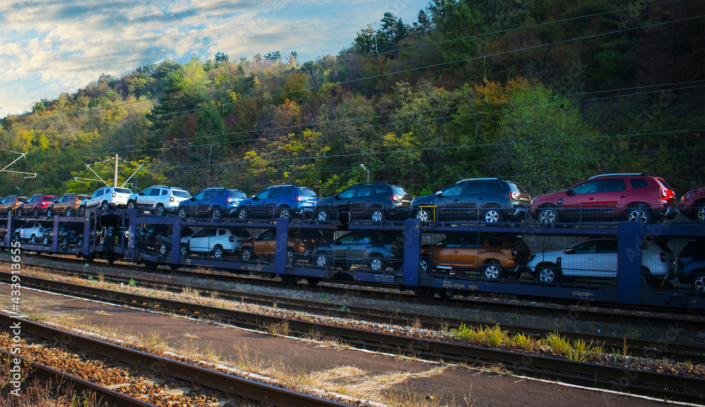 Many cars transported by train. Automotive industry, export- concept. No logo, brand.