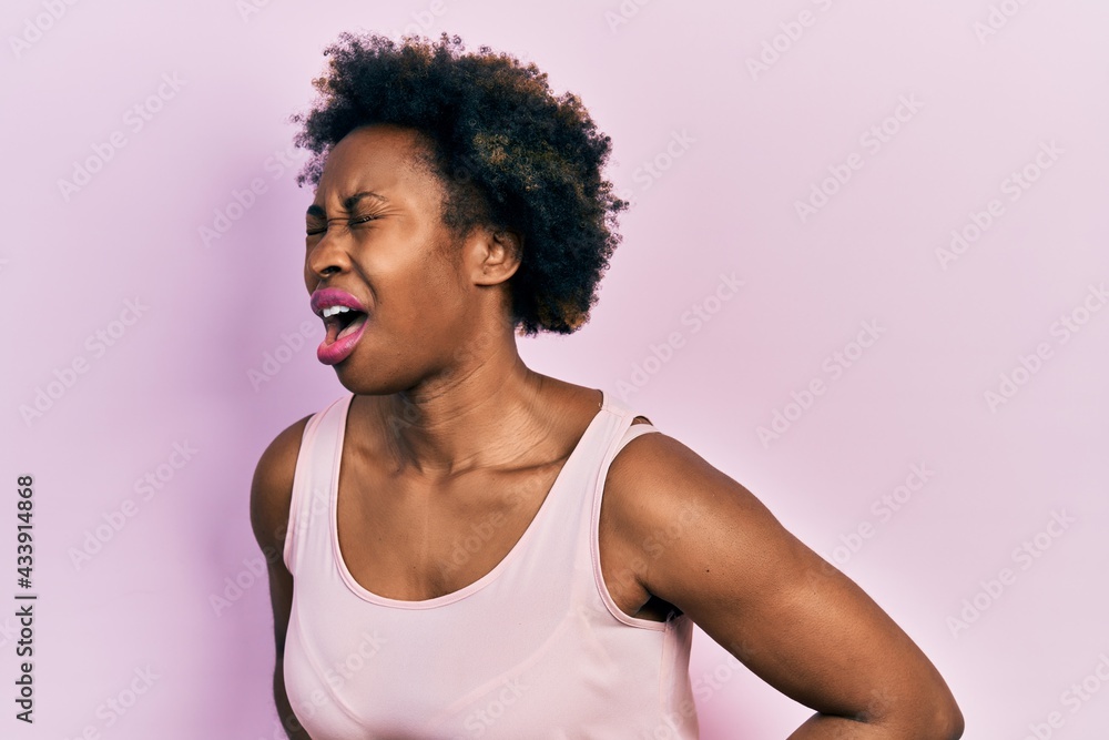 Young african american woman wearing casual sleeveless t shirt with hand on stomach because nausea, painful disease feeling unwell. ache concept. Young african american woman wearing casual sleeveless t shirt with hand on stomach because nausea, painful disease feeling unwell. ache concept.