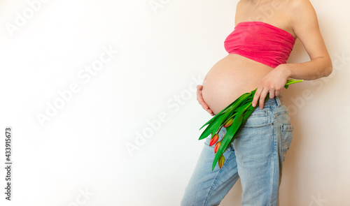 Pregnant belly with a bouquet of flowers. The joy and happiness of motherhood pregnant girl in anticipation of the baby.