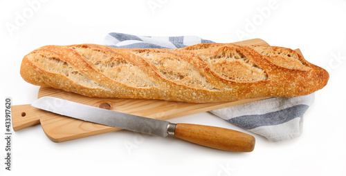 Sourdough baguette and knife on cutting board isolated on white background, closeup. Organic bread with type 1 flour.