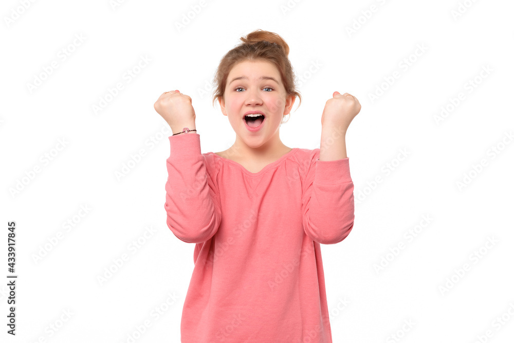 Cheerful young girl raising her fists with smiling delighted face, yes gesture, celebrating success Cheerful young girl raising her fists with smiling delighted face, yes gesture, celebrating success