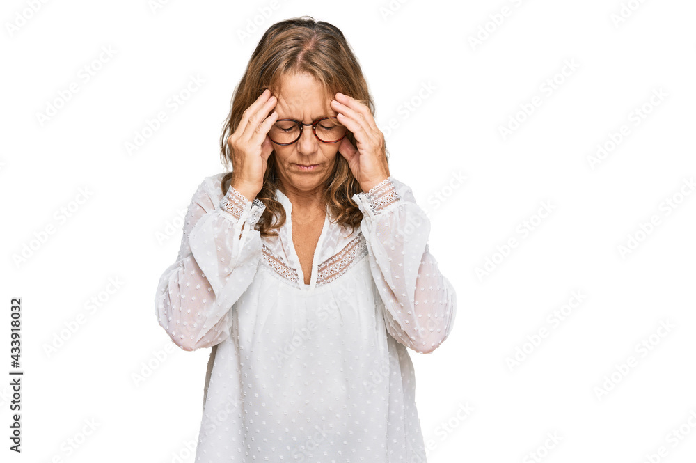 Middle age blonde woman wearing casual white shirt and glasses with hand on head for pain in head because stress. suffering migraine. Middle age blonde woman wearing casual white shirt and glasses with hand on head for pain in head because stress. suffering migraine.