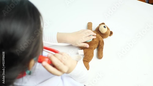 Asian children girl role-play as doctor check bear health