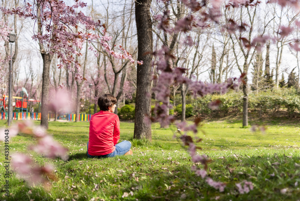 Attractive young female sitting on the grass in a park during early spring Attractive young female sitting on the grass in a park during early spring