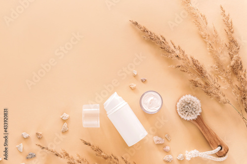 Organic natural cosmetics and wooden face brush with dry grass decoration on beige background. Top view, flat lay. Copy space